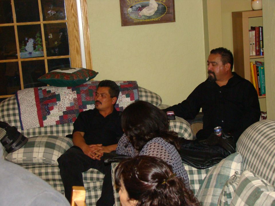 People gathered indoors on couches, with a window showing a snowman decoration