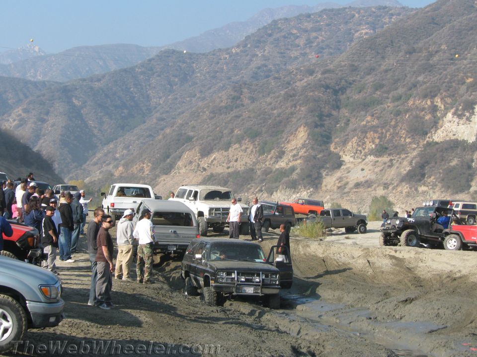 Off-road vehicles stuck in mud with spectators watching in a canyon