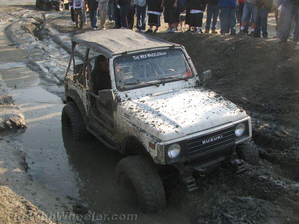 1987 Suzuki Samurai stuck in mud, with "The Web Wheeler.com" sticker on windshield