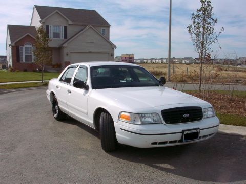 1999 Ford Crown Victoria - A white Ford Crown Victoria sedan is parked in front of a suburban house.