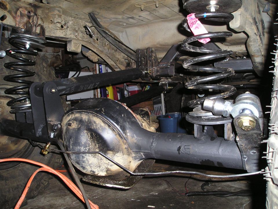 Rear axle assembly with aftermarket suspension components, including coil springs and control arms