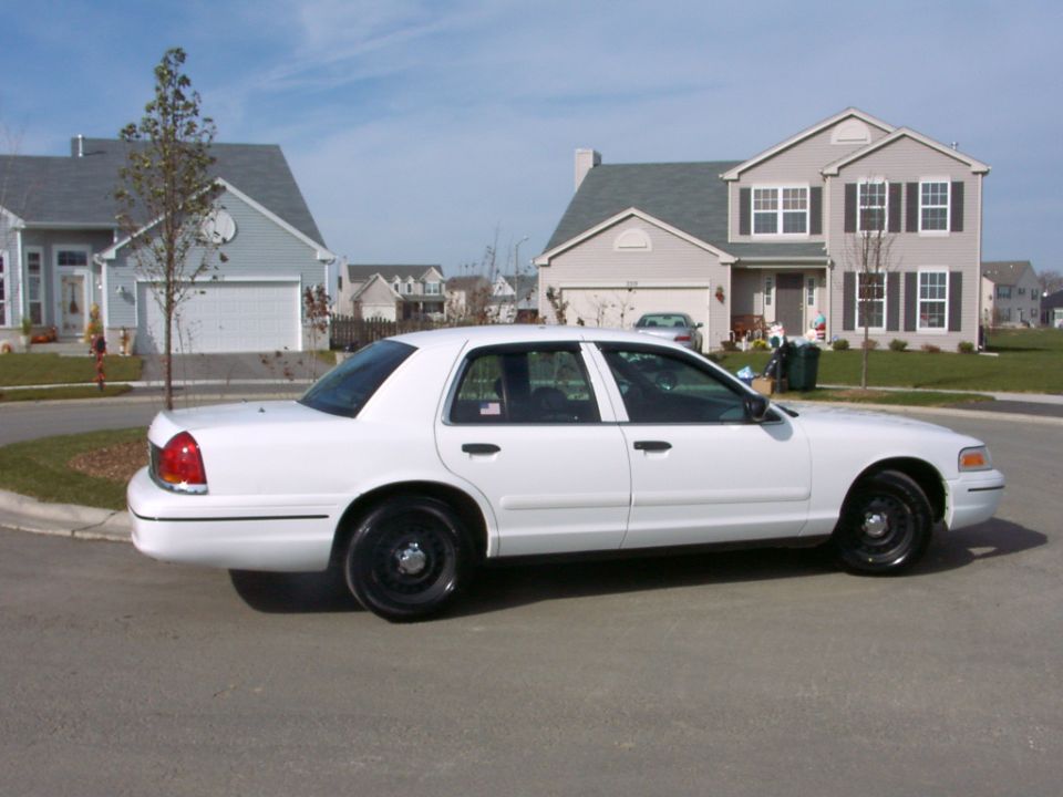 White Ford Crown Victoria parked on suburban street, side view