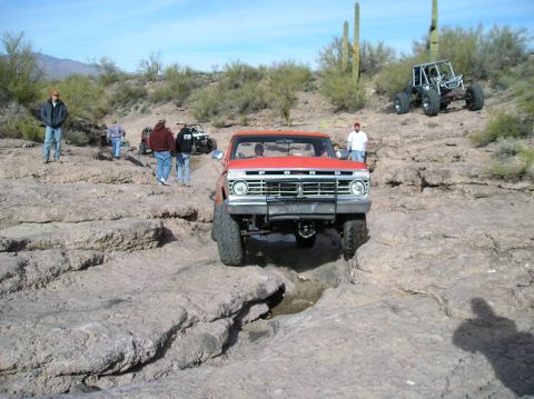 1986 Toyota Hilux - A group of off-road vehicles and people are seen in a desert landscape with rocky terrain and saguaro cacti.
