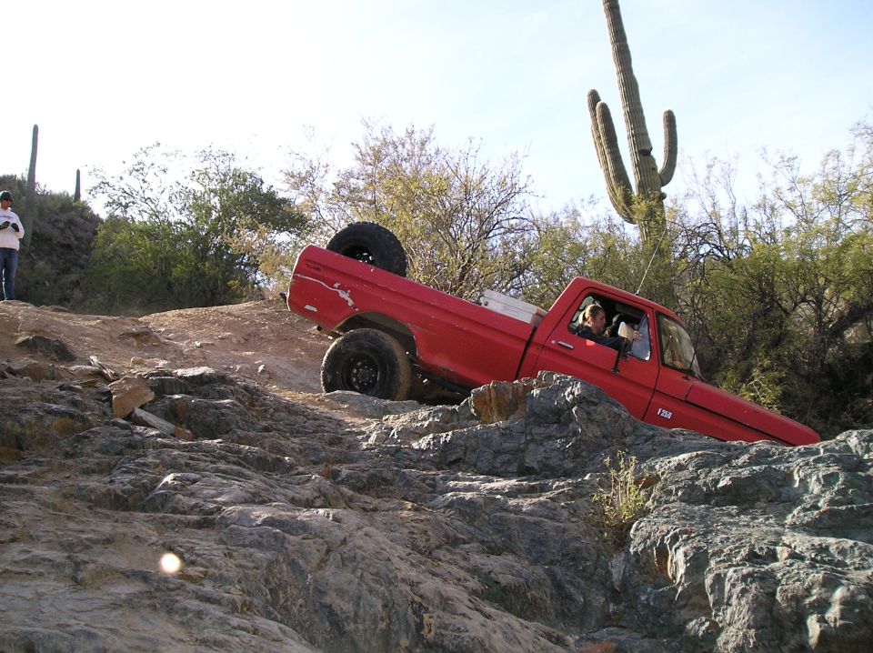 Red 1979 Ford F-150 off-roading on a rocky desert trail