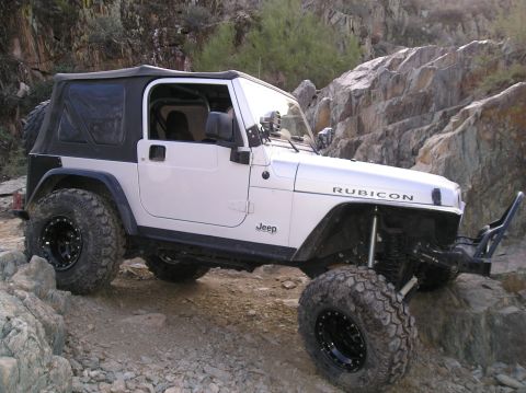1986 Toyota Hilux - A white Jeep Wrangler Rubicon navigates a rocky trail, its off-road capabilities.