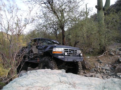 1986 Toyota Hilux - Modified Ford F-Series truck navigating a rocky desert trail with a saguaro cactus nearby.