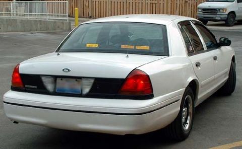 1999 Ford Crown Victoria - A white sedan is parked outdoors, with another vehicle visible in the background.
