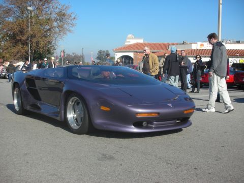 1998 Ford Crown Victoria - A unique purple sports car is the focus of this scene, with onlookers gathered around.