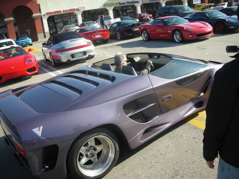 Rear of a purple Vector supercar with louvered engine cover at a street show