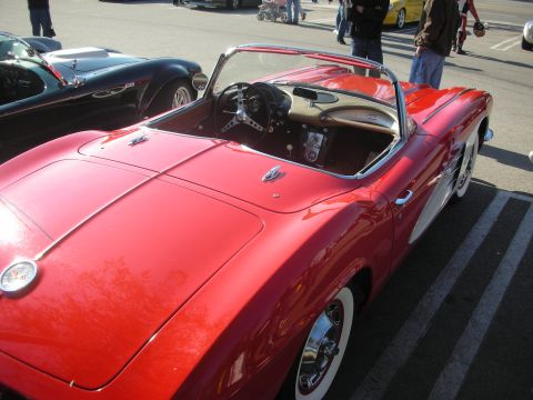 1998 Ford Crown Victoria - A red convertible sports car with classic styling and whitewall tires is parked at an outdoor event.
