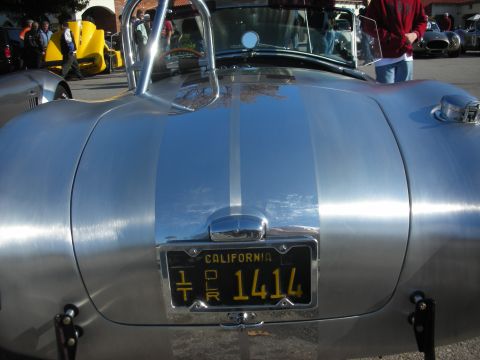 1998 Ford Crown Victoria - Rear view of a polished silver sports car at an outdoor gathering with other vehicles.