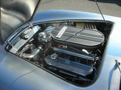 1998 Ford Crown Victoria - The engine bay of a silver Cobra 427 is open, revealing its powerful V8 engine and polished components.