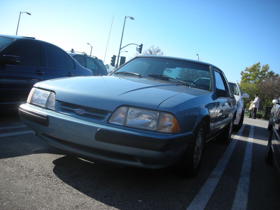 Light blue Fox-body Ford Mustang sedan parked in a lot