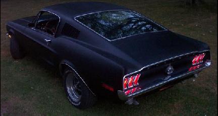 1968 Ford Mustang - A black 1968 Ford Mustang coupe is parked on grass, viewed from a high rear 3/4 angle.