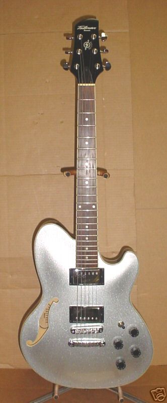1995 Ford Bronco - This is a silver electric guitar with a black headstock and fretboard, displayed on a stand.