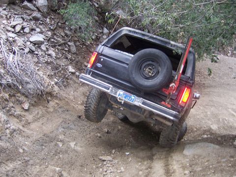 1981 Ford Bronco - A black Ford Bronco navigates a steep, rocky trail with a Hi-Lift jack attached to the rear.