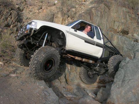 1986 Toyota Hilux - Modified 1986 Toyota Hilux navigating a rocky trail with large tires and suspension.