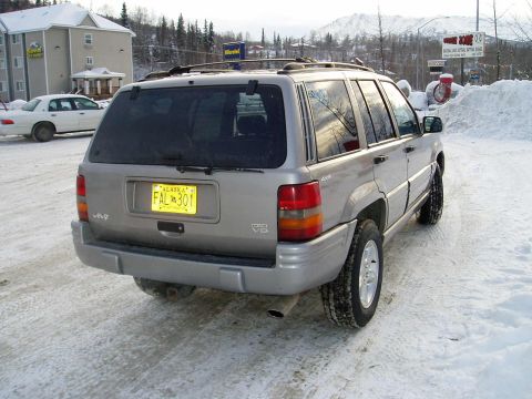2000 Ford E350 - Silver Jeep Grand Cherokee in snowy conditions with an Alaska license plate.