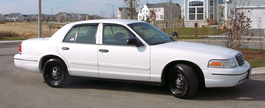 White 1999 Ford Crown Victoria sedan parked on street, side view