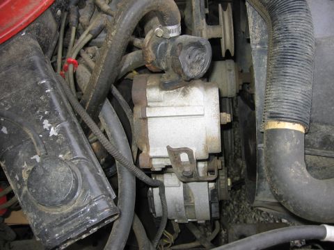 1987 Ford Bronco - This image shows a close-up view of an engine compartment with an alternator and several hoses visible.