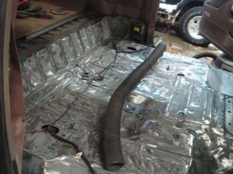 1996 Ford Bronco - The bare metal floor of a vehicle interior, showing exposed metal and some wiring, with another vehicle visible in the background.