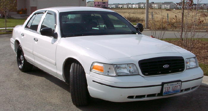 White sedan, front 3/4 view, parked on asphalt. License plate visible