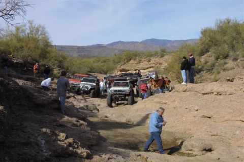 1994 Ford Bronco - A group of off-road vehicles navigate a challenging desert terrain with onlookers.