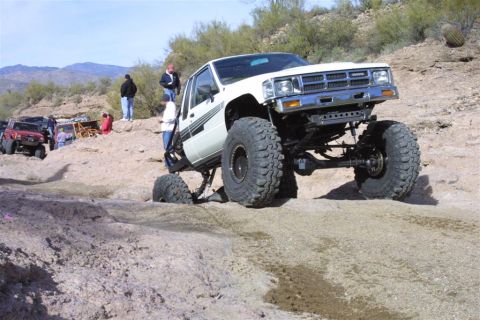 1994 Ford Bronco - A white 1984 Toyota 4x4 navigates a rocky off-road course with other vehicles in the background.