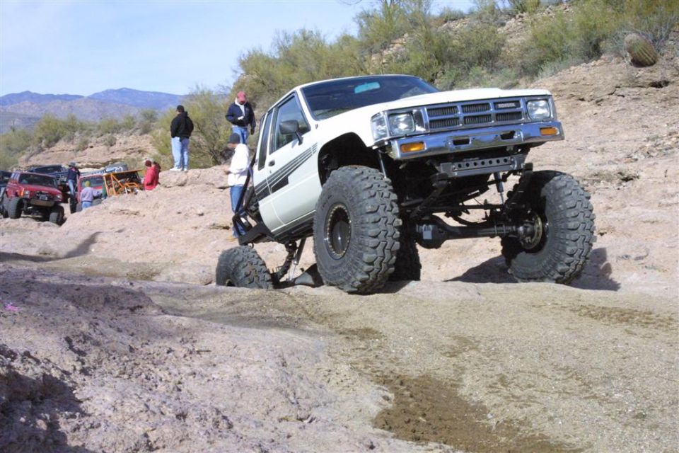 White 1984 Toyota 4x4 off-roading with large tires