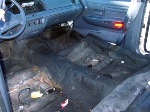 1999 Ford Crown Victoria - The interior of a 1999 Ford Crown Victoria shows a worn dashboard and carpeting, indicating significant use.