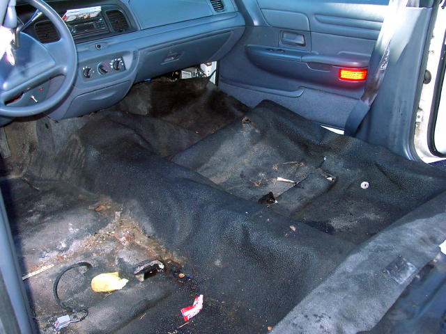 Interior of a 1999 Ford Crown Victoria with worn carpeting and dashboard