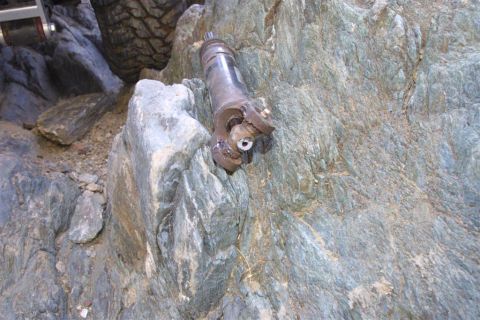 1994 Ford Bronco - A damaged vehicle part is shown lodged among rocks, with a tire visible in the background.