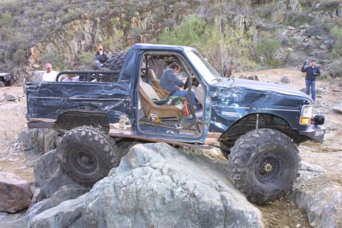 1994 Ford Bronco - This heavily modified SUV is navigating a rocky trail with its doors removed and large off-road tires.