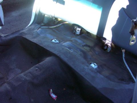 1999 Ford Crown Victoria - The floor of a car's interior is visible, with carpeting removed and seat mounting points exposed.