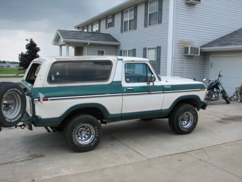 1979 Ford Bronco - A two-tone Ford Bronco is parked in front of a house, with a motorcycle visible to the right.