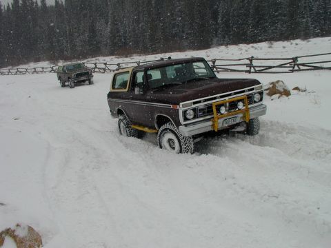 1979 Ford Bronco - A brown Ford Bronco navigates through deep snow, with another vehicle following in the background.
