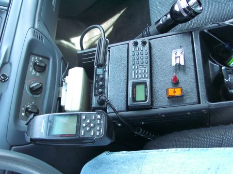 1999 Ford Crown Victoria - Interior view of a vehicle's center console equipped with police radio equipment and a flashlight.