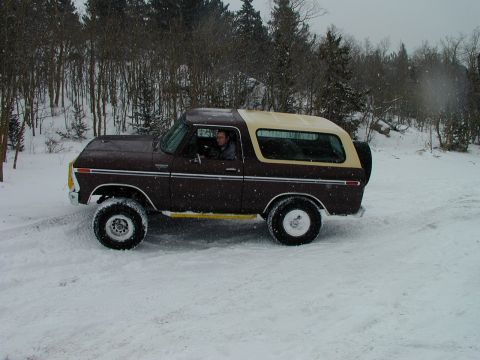 1979 Ford Bronco - A 1979 Ford Bronco navigates a snowy landscape, its two-tone paint contrasting with the wintery surroundings.