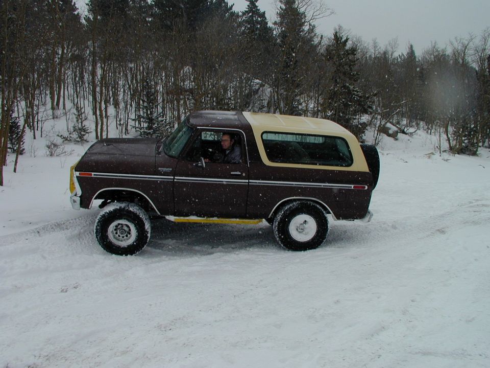 Brown and tan 1979 Ford Bronco driving in snow