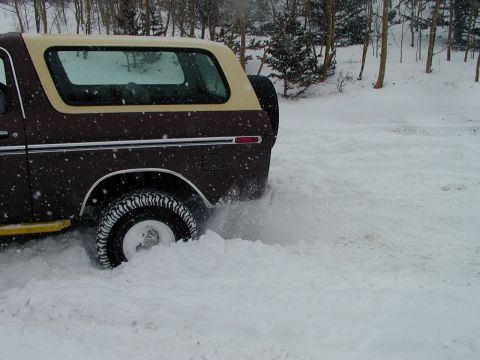 1979 Ford Bronco - Ford Bronco driving through deep snow, kicking up a spray.