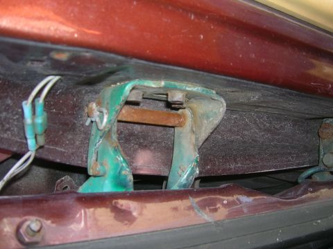 1979 Ford Bronco - This photo shows a close-up view of a vehicle's door hinge, which appears to be rusted and has electrical wires connected to it.