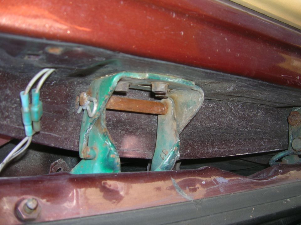 Close-up of a rusty green door hinge with wires attached