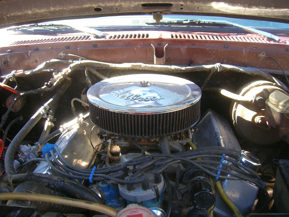 V8 engine bay with chrome Edelbrock air cleaner, carburetor and blue plug wires