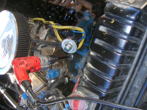 1979 Ford Bronco - A close-up view of an engine bay shows a drill in operation near the valve cover and radiator.