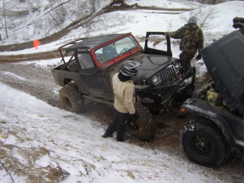 1992 Ford Bronco - Off-road vehicles navigate a challenging muddy and snowy terrain with assistance from onlookers.