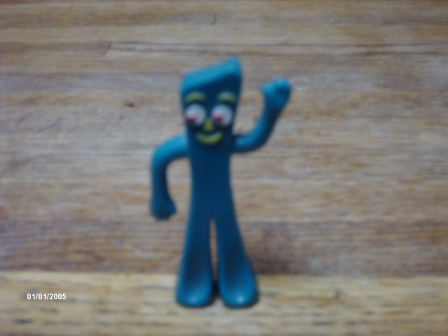 Blue Gumby figurine with red eyes and yellow smile, waving