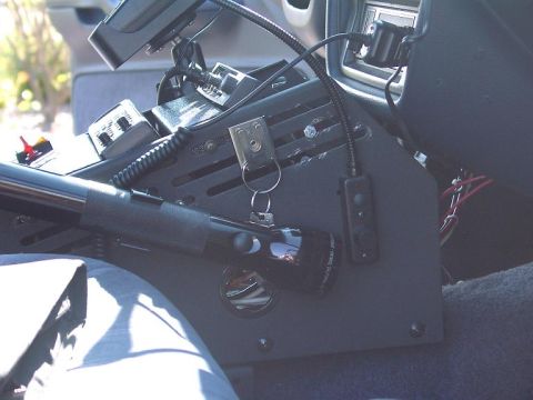 1999 Ford Crown Victoria - Close-up of a vehicle's center console, showing various mounted electronic devices and a flashlight.