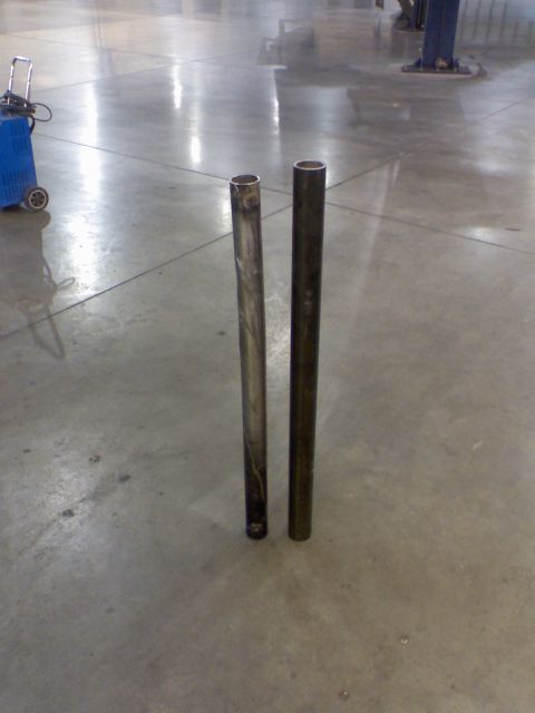 1974 Ford F-250 - Two metal pipes are shown standing upright on a concrete floor, possibly for automotive repair or fabrication.