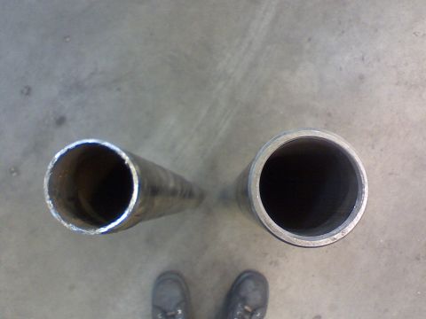 1974 Ford F-250 - Two metal pipes are shown on a concrete surface, with a person's feet visible at the bottom.
