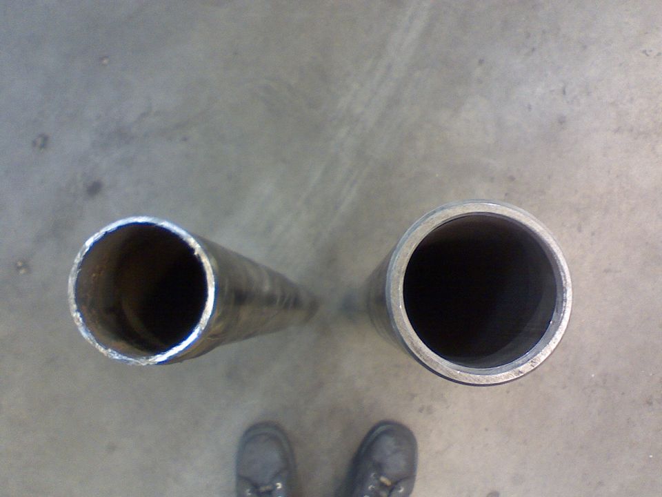 Two metal pipes, one wider than the other, lying on a concrete floor